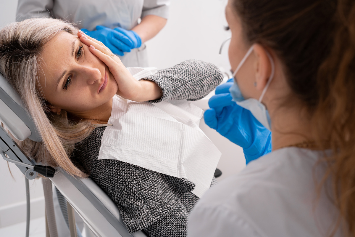 beautiful caucasian girl with toothache sits in a dental chair. Professional dentist helps his female patient in pain.painful treatment help.