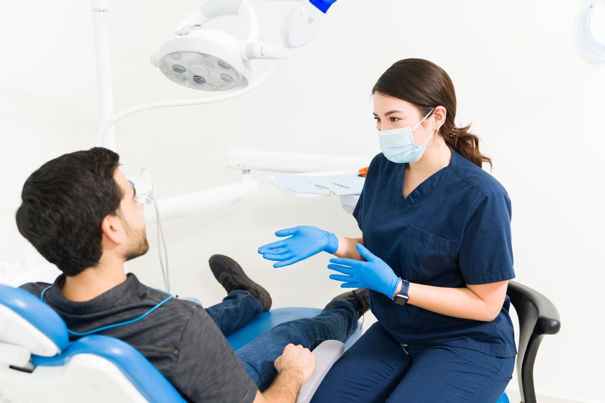 Young woman dentist talking about a treatment with a patient